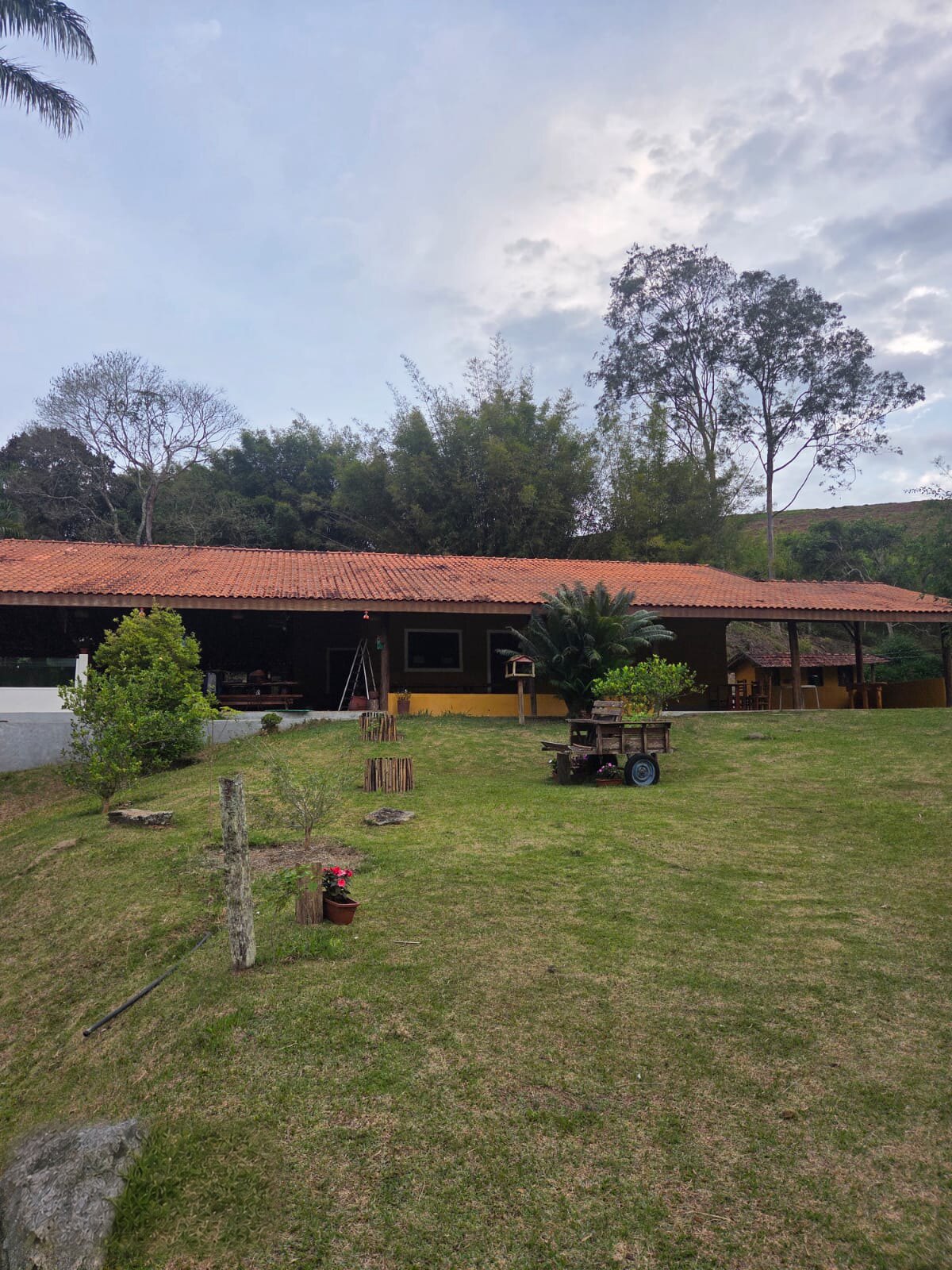 Varanda coberta da casa sede com aquário de azulejos, flores e o lago ao fundo